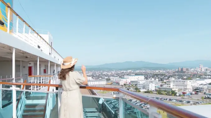 クルーズ船のデッキから港町を眺める女性